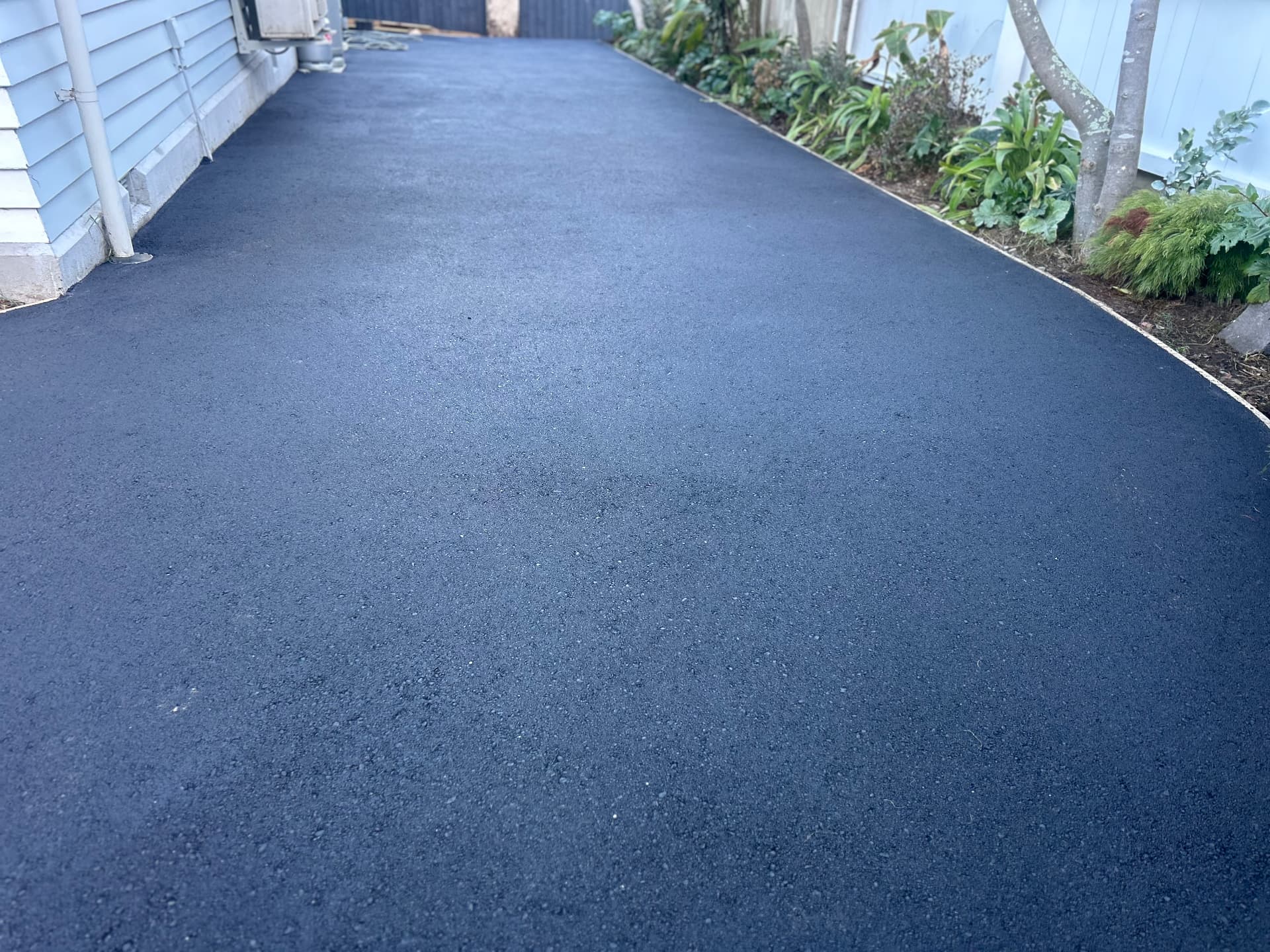 Newly laid asphalt driveway running alongside a Canterbury home