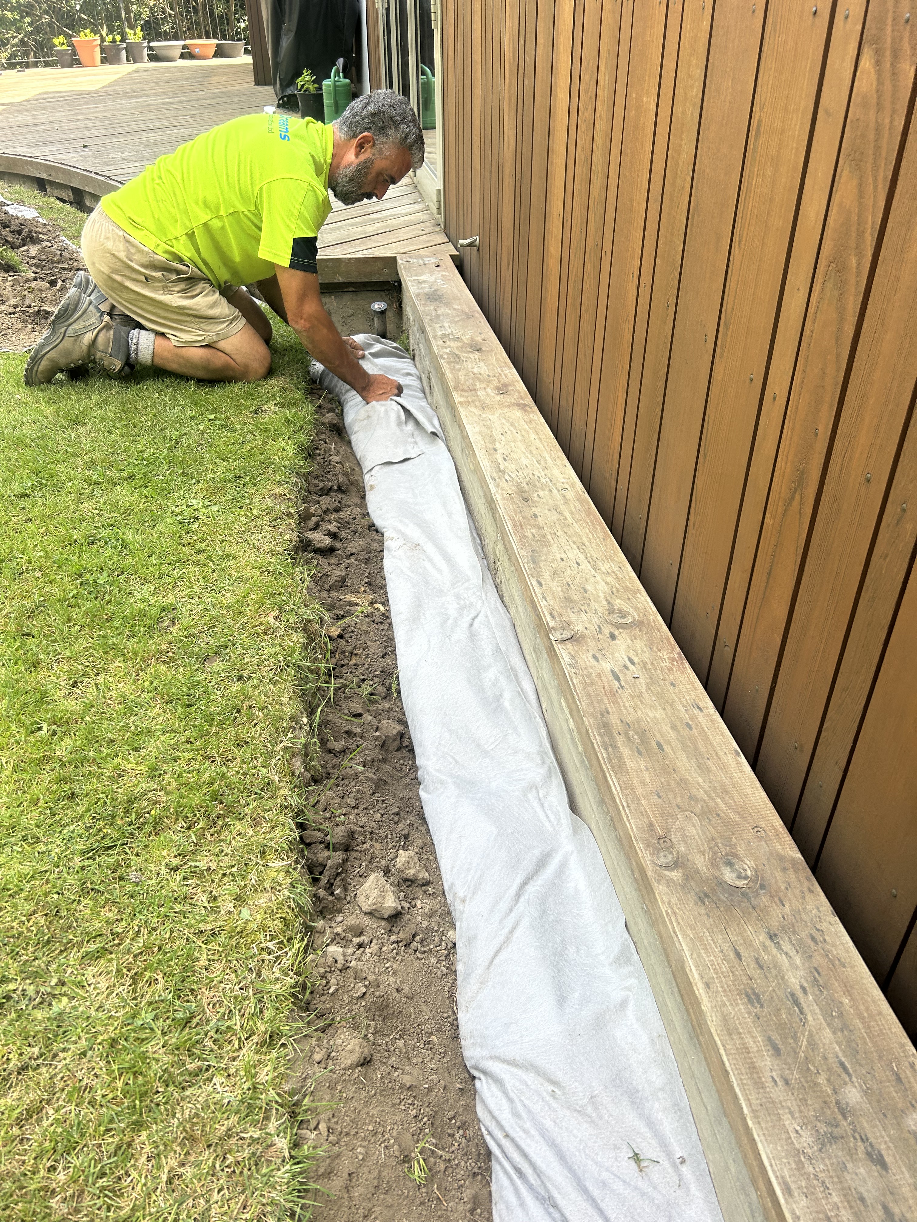 French drain installation — perforated pipe and geotextile wrap laid before backfilling
